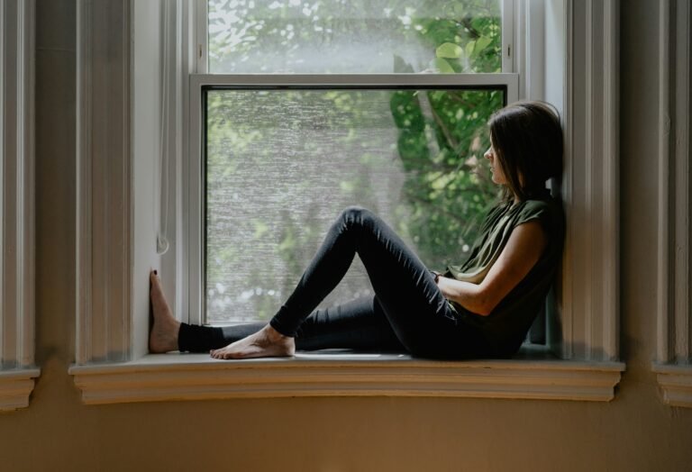 Woman sitting by a window in quiet reflection